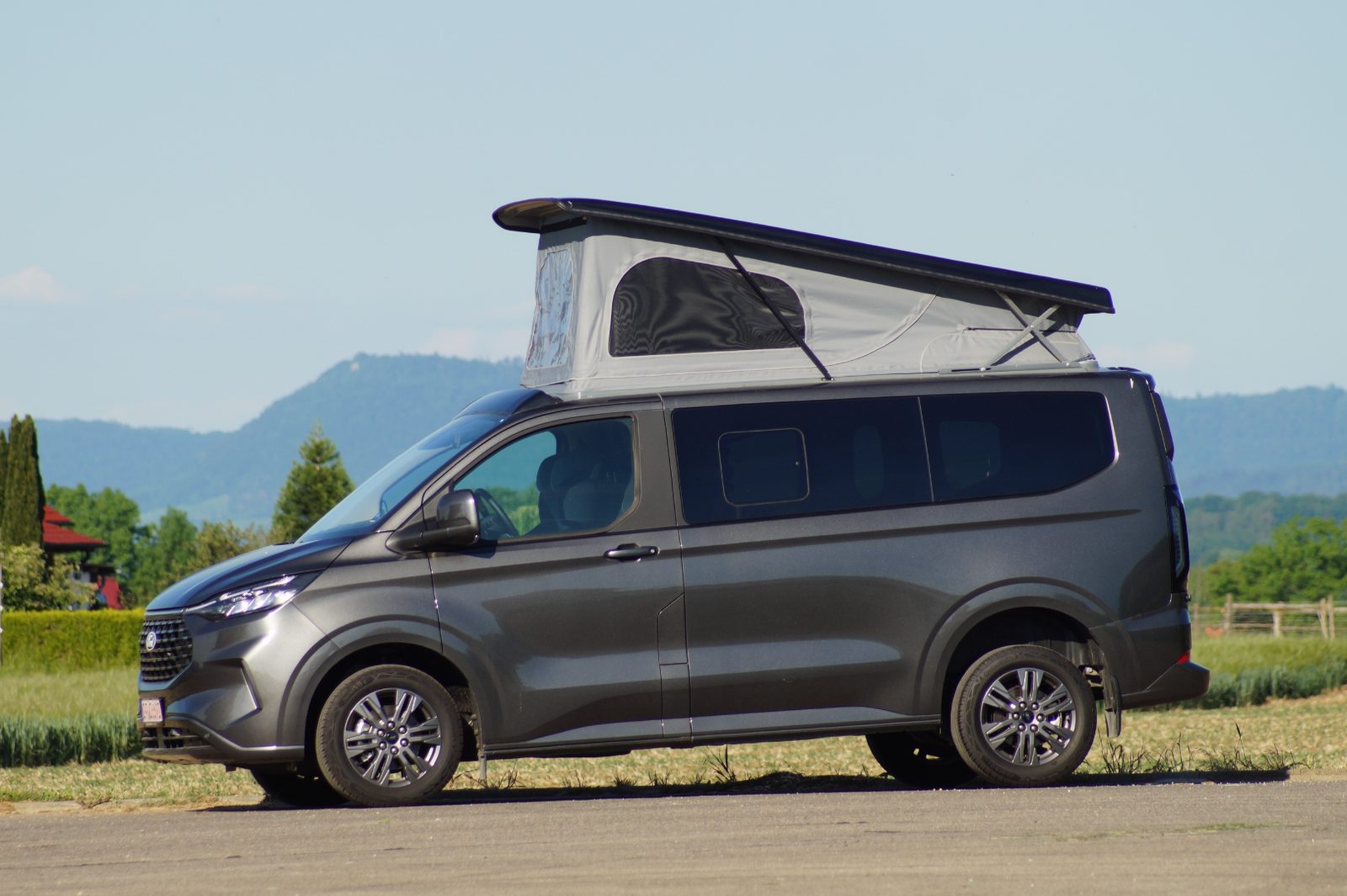 Grauer Dein Held Ford Tourneo Custom Titanium mit Aufstelldach im Grünen